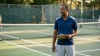 Homme entraîneur souriant tenant un presse-papiers sur court de tennis