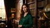 Femme en chemise verte posant dans une bibliothèque avec livres anciens