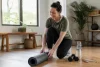 Une femme range son tapis après une séance avec haltères dans une pièce lumineuse.