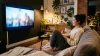 Femme regardant la télévision avec du popcorn sur un canapé