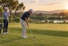 Un golfeur travaille une approche courte près d'un green sous le regard d'un coach.