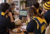 Supporters de rugby anonymes discutant autour d’un ordinateur à l’écran flouté.