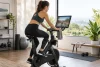 Adulte utilisant un vélo de spinning connecté générique dont l’écran est flouté.